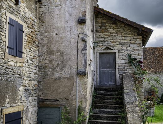 Maison de village en pierre et son escalier extérieur sous un ciel d'orage, photo de démonstration