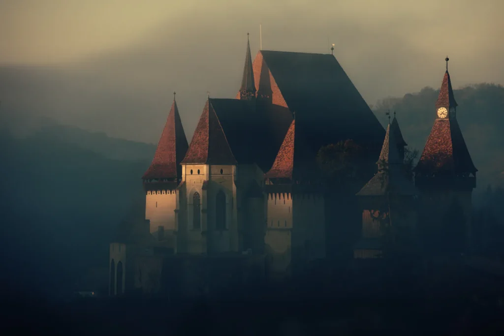 Château gothique aux fenêtres éclairées dans la brume du soir
