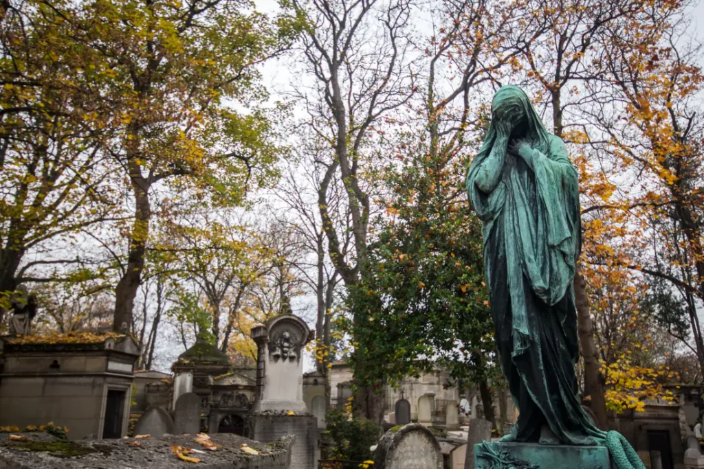 Statue de bronze voilée qui pleure parmi les tombes du cimetière du Père-Lachaise, à Paris, en automne